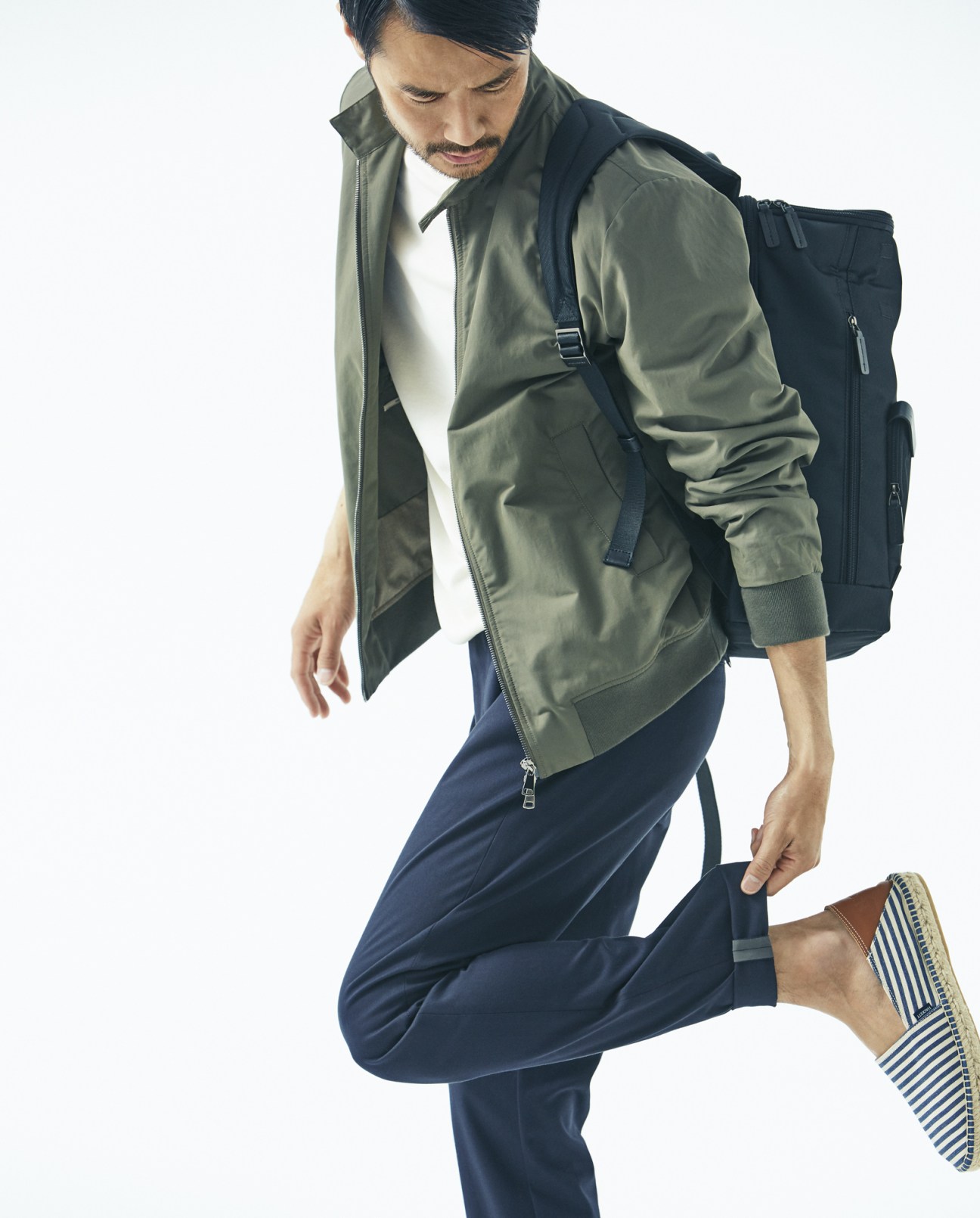 Man wearing olive Valstar jacket, navy Emporio Armani trousers, and striped Hackett London espadrilles with Piquadro backpack