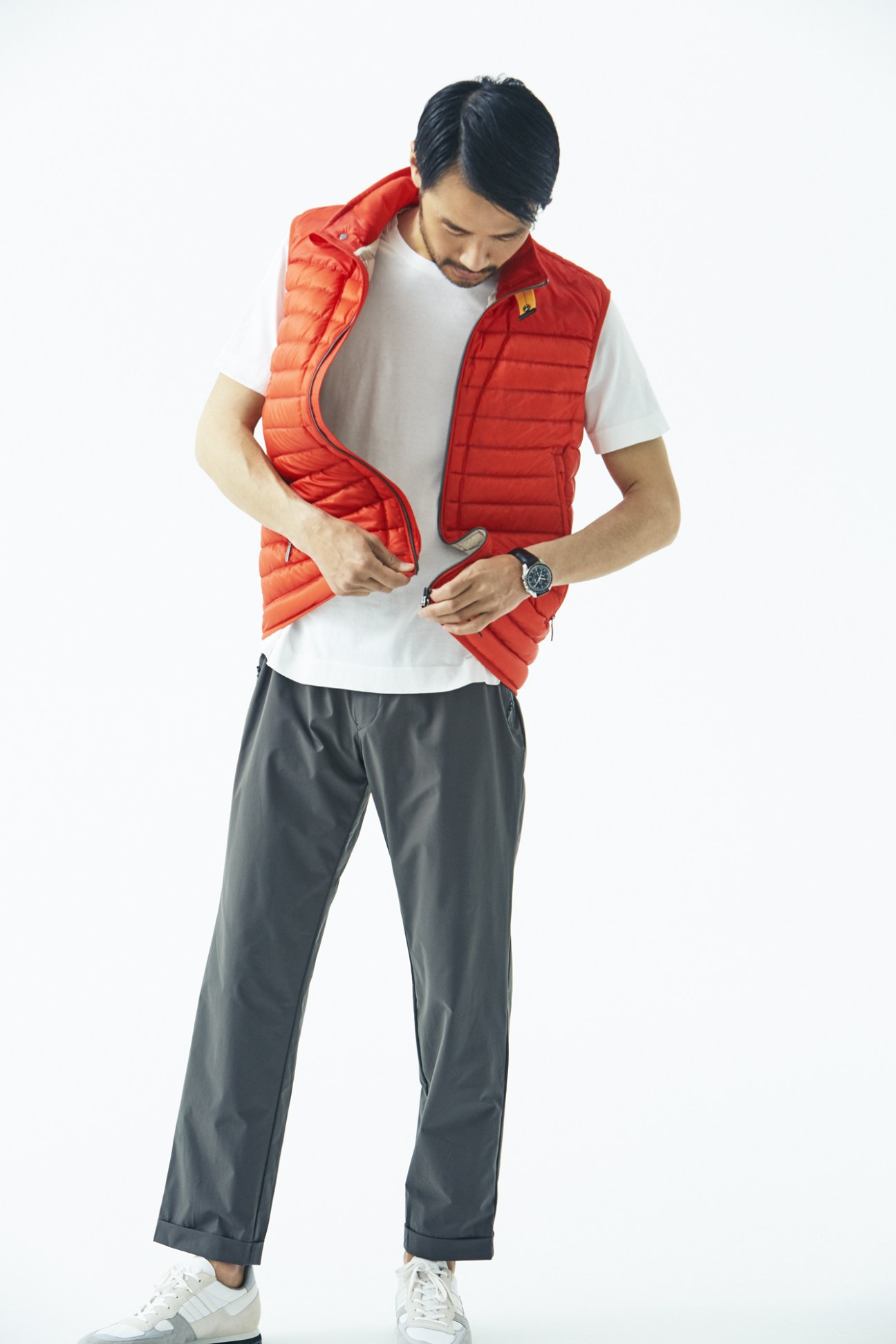 Male model wearing red Parajumpers down vest, white Circolo 1901 t-shirt, grey Descente Pause trousers, and Omega watch.
