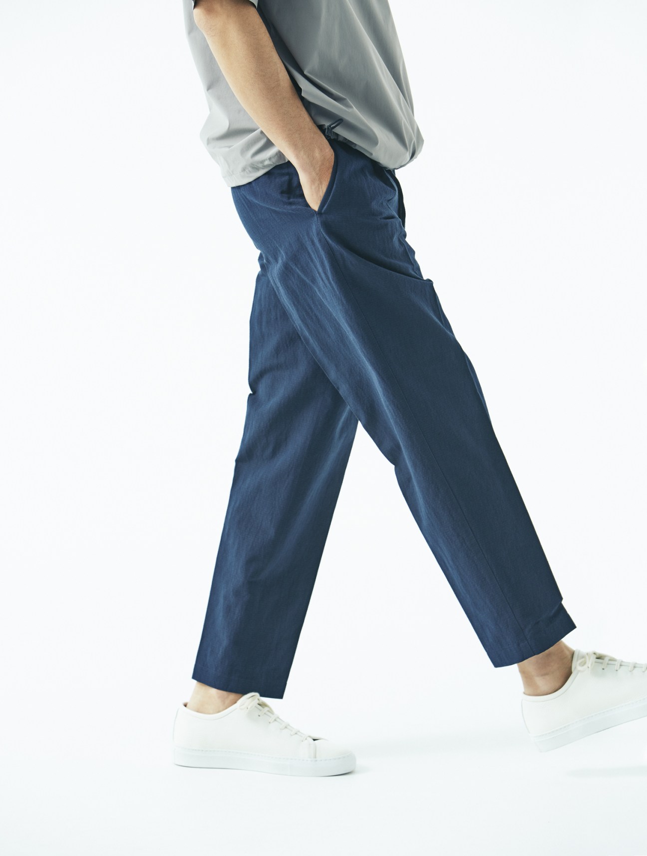 Male model wearing light blue shirt, navy trousers by The Gigi, and white trainers by United Arrows.