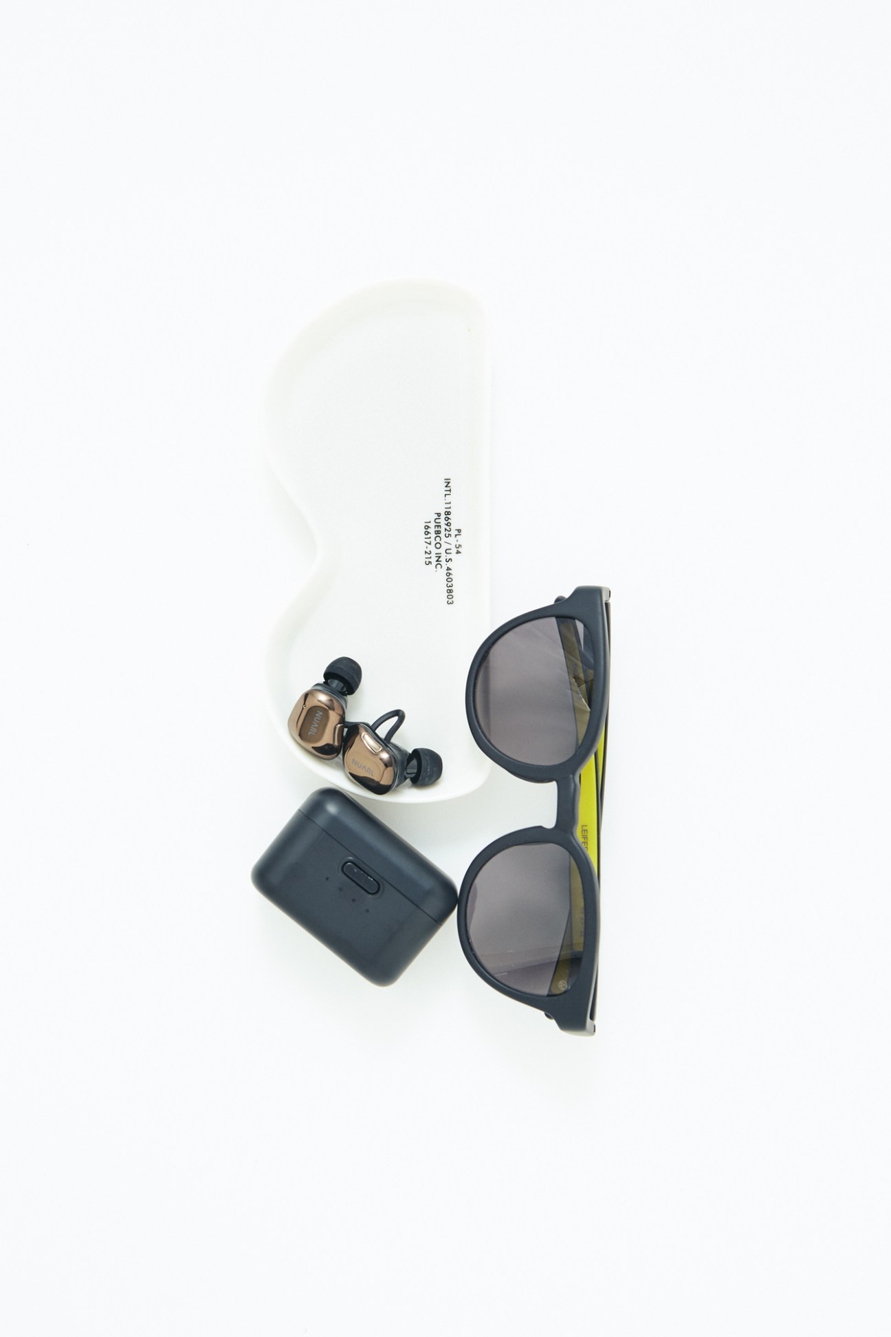 Eyevol sunglasses, Puebco glasses dish, and Nuarl earphones arranged on white background