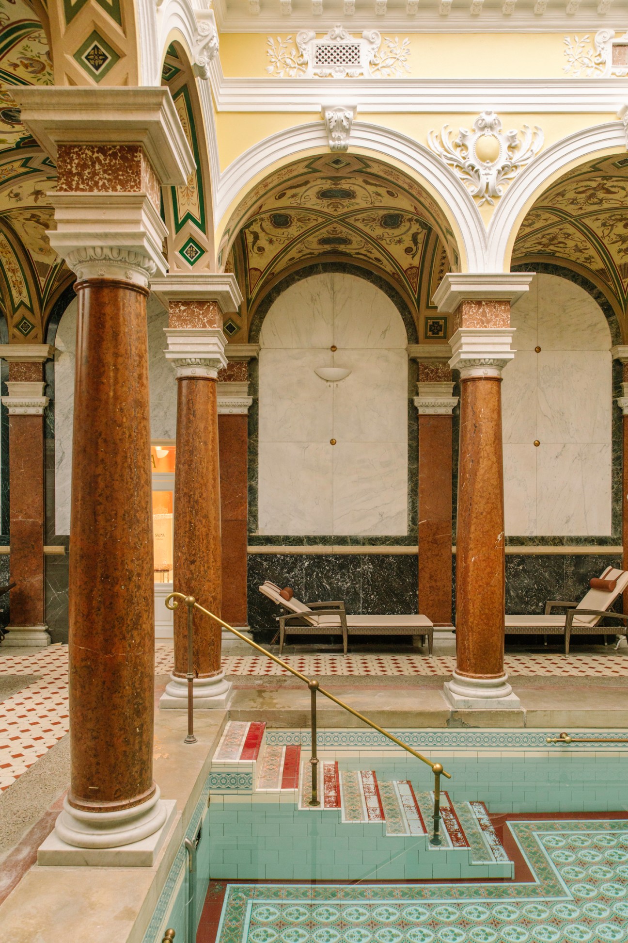 Ornate Roman Spa with marble columns, arched ceilings, decorative tilework and a sunken pool area