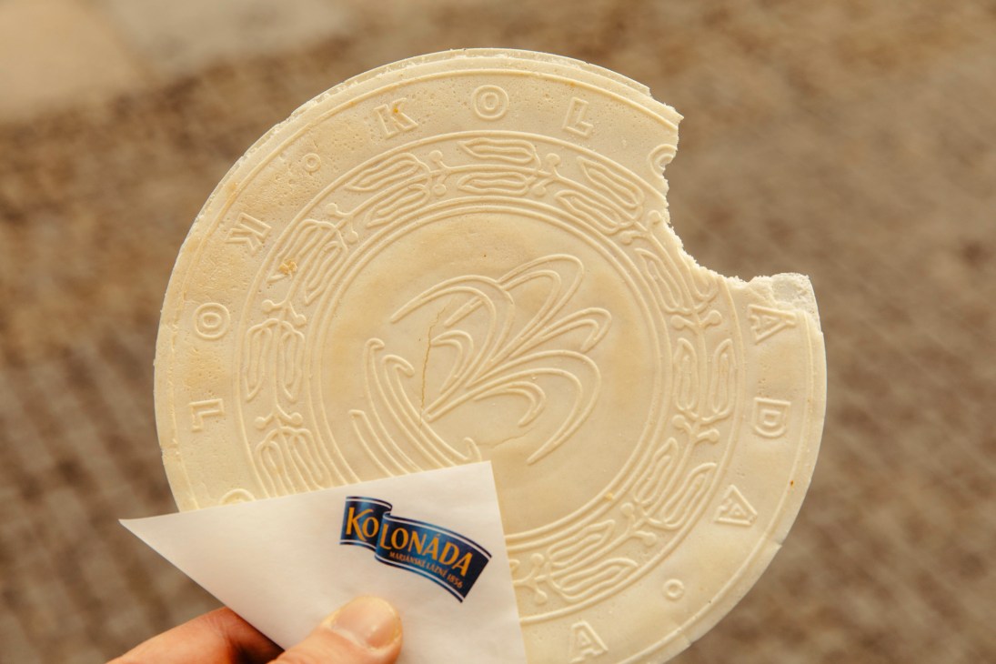 Traditional Czech spa wafer with ornate circular pattern being held with Kolonada brand label visible