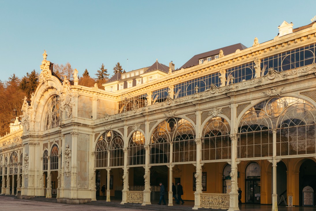 Cast-iron colonnade with ornate arches and glass ceiling in golden sunlight