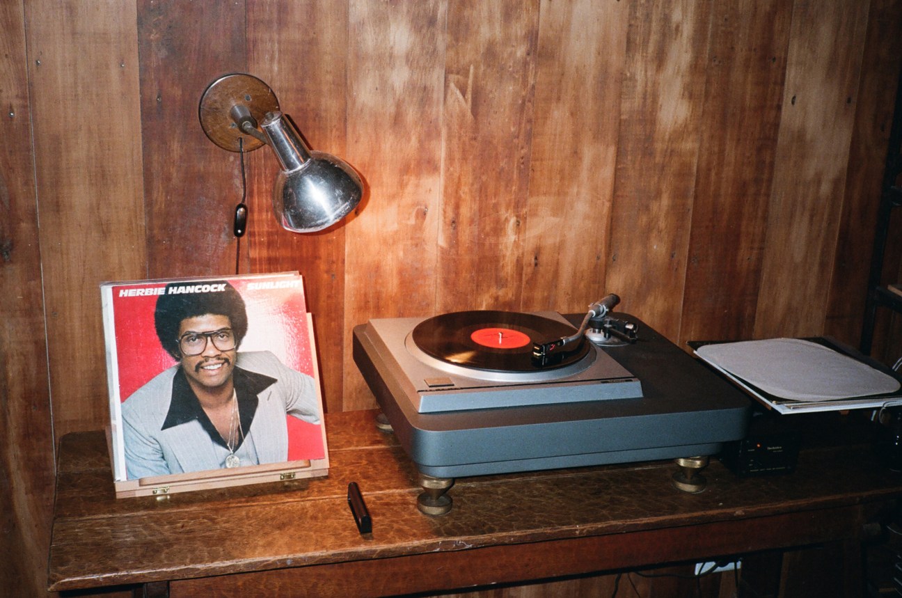 Herbie Hancock vinyl record with turntable and vintage lamp on wooden shelf.
