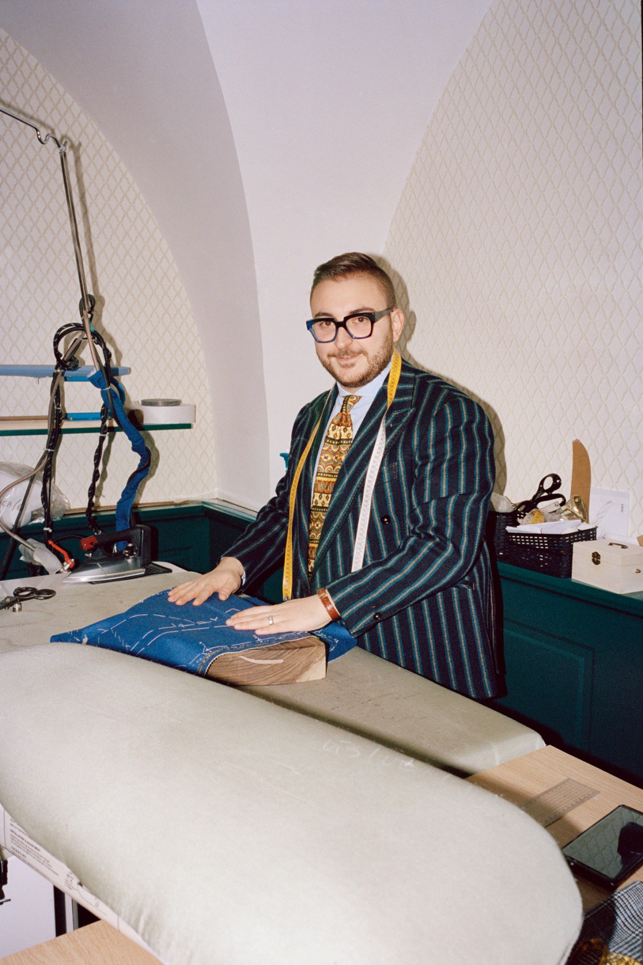 Andrea Franchini, a young tailor, examines fabric samples at his workbench in his tailoring workshop.