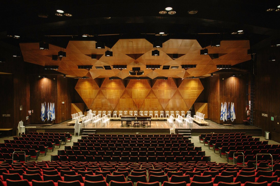 Interior of Churchill Auditorium at Technion with wooden geometric ceiling, red seating, and stage.