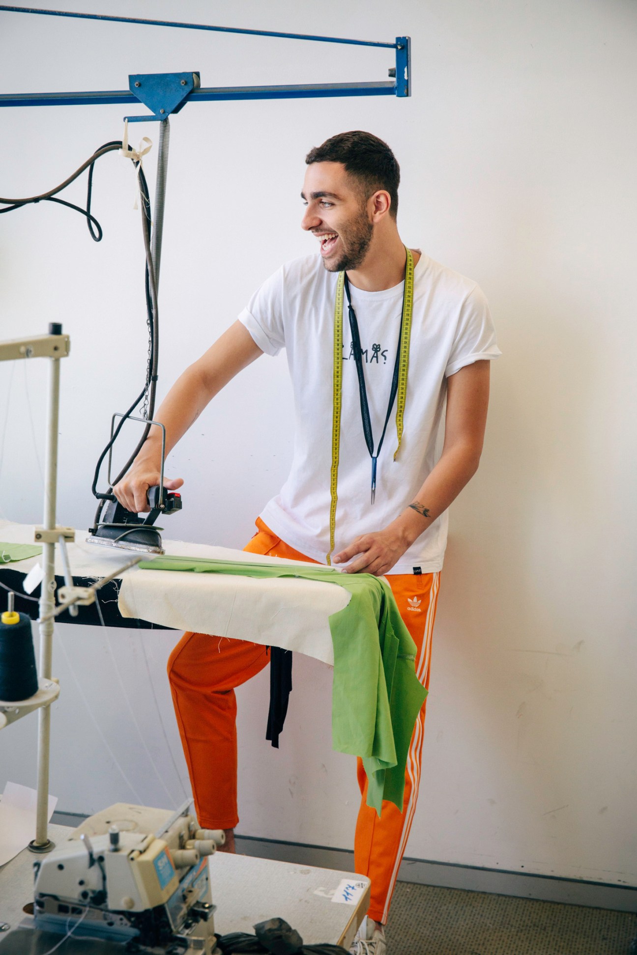 A male fashion student uses a steamer on fabric at a work table in Shenkar College's fashion department.
