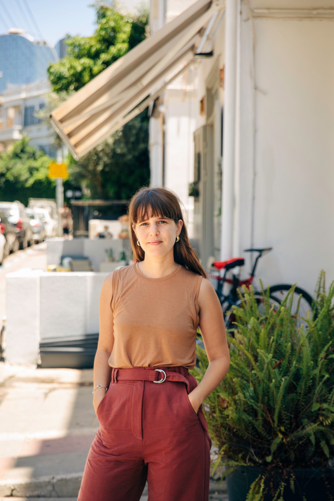 Designer Noy Goz standing outside a storefront on a Tel Aviv street.