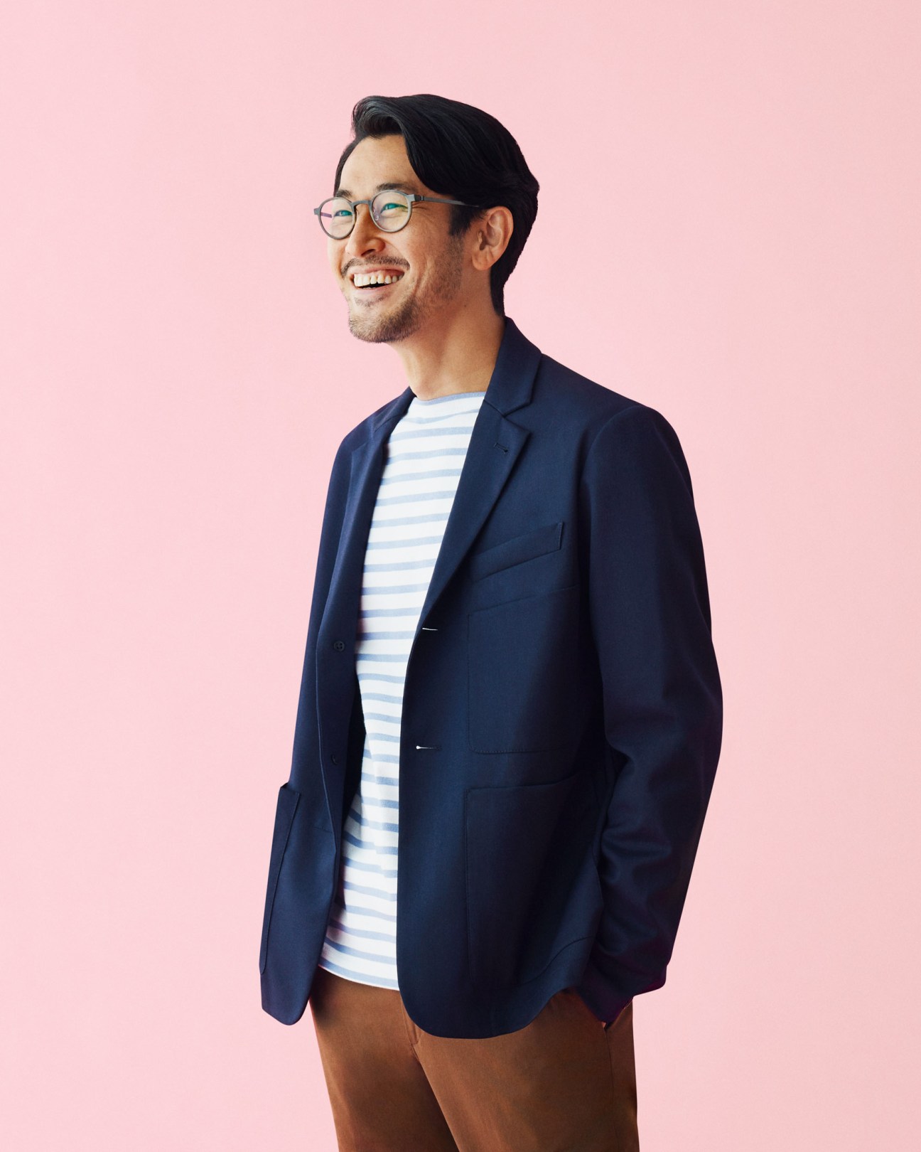 Man wearing navy Barena jacket, striped Orcival t-shirt, Ermenegildo Zegna trousers, and Lindberg glasses against pink background.