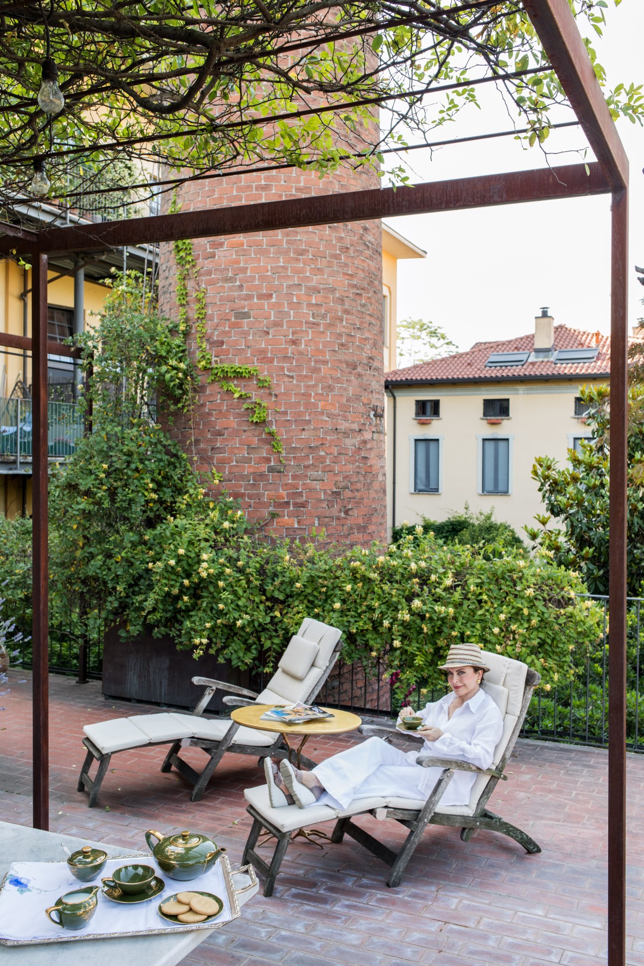 Woman relaxing on a rooftop terrace surrounded by climbing vines and lush greenery in Milan.