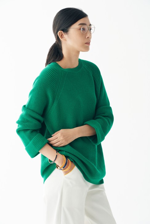 Woman wearing a green ribbed jumper by Red Valentino with Hermès bracelets and Lindberg glasses.