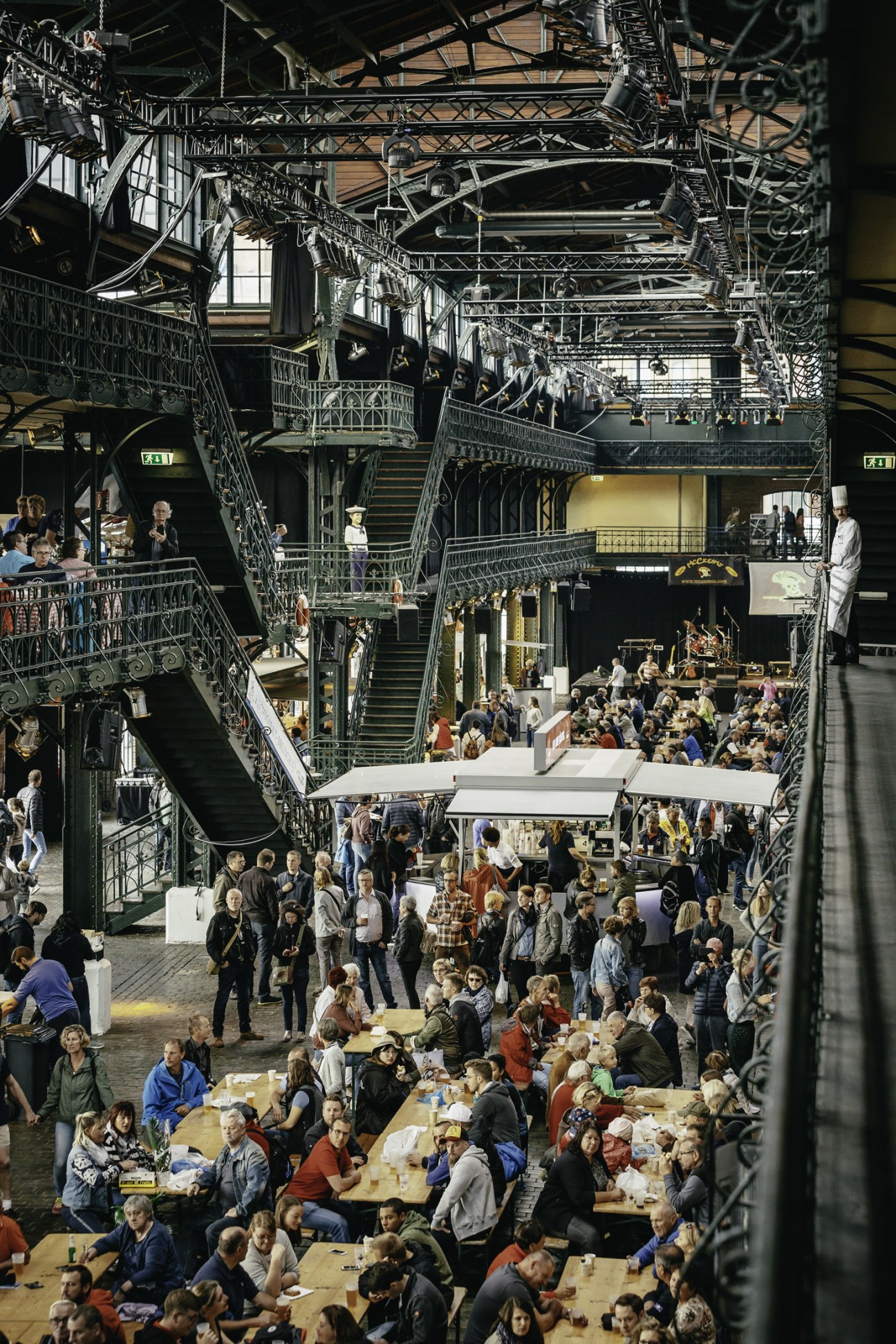 Overhead view of the Hamburg Fish Market's interior auction hall filled with crowds of people seated at long tables eating and drinking.