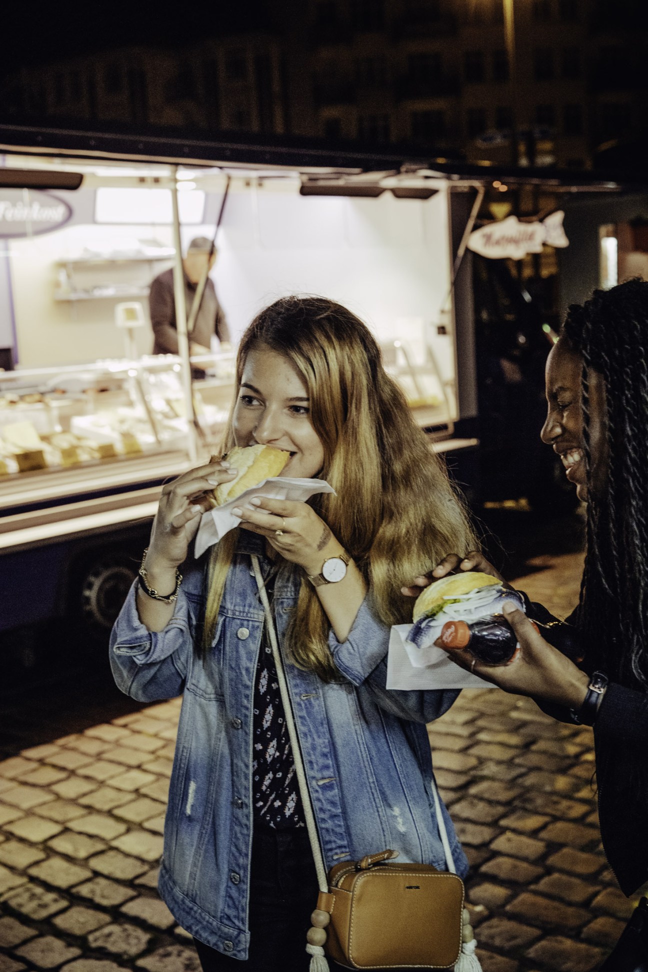 Young woman eating a herring roll at Hamburg Fish Market early morning