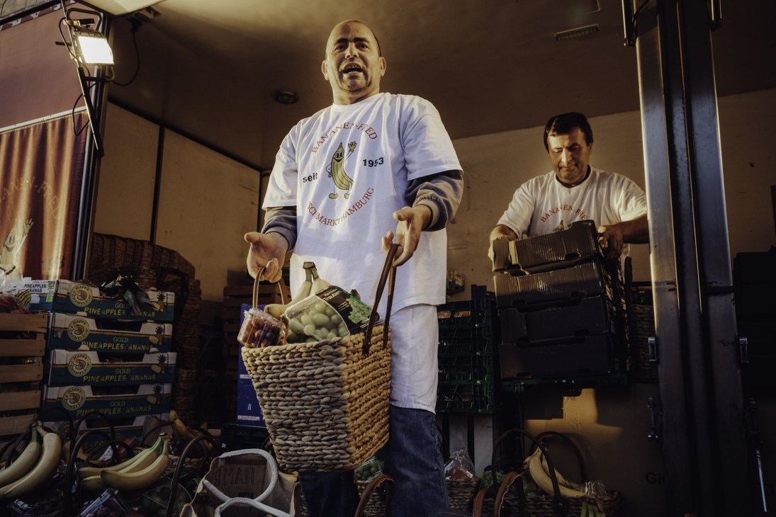 Vendor holding a large woven basket filled with fruit at Hamburg Fish Market.