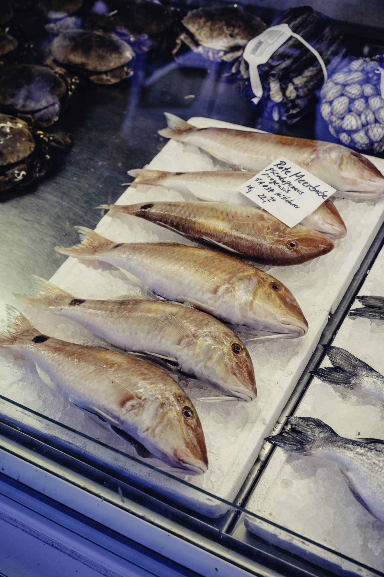 Fresh whole fish displayed on ice at a market stall with a price label.