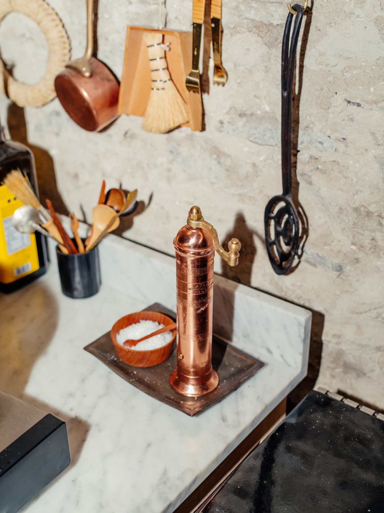Copper coffee grinder with hand crank on marble kitchen counter