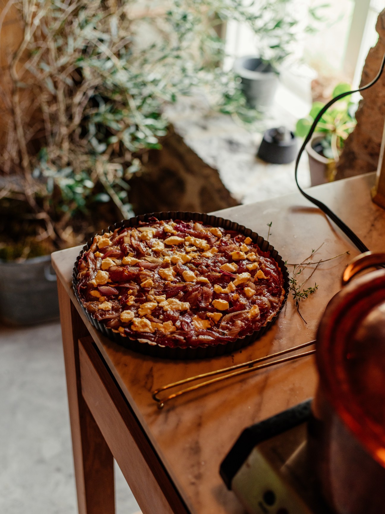 Onion tart with goat's cheese in a fluted tart pan on a wooden cutting board