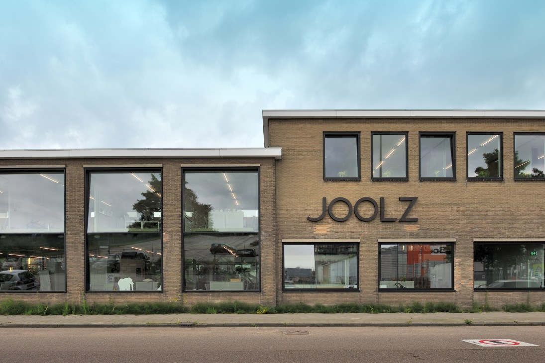 Modern brick building with large glass windows displaying Joolz signage on the facade