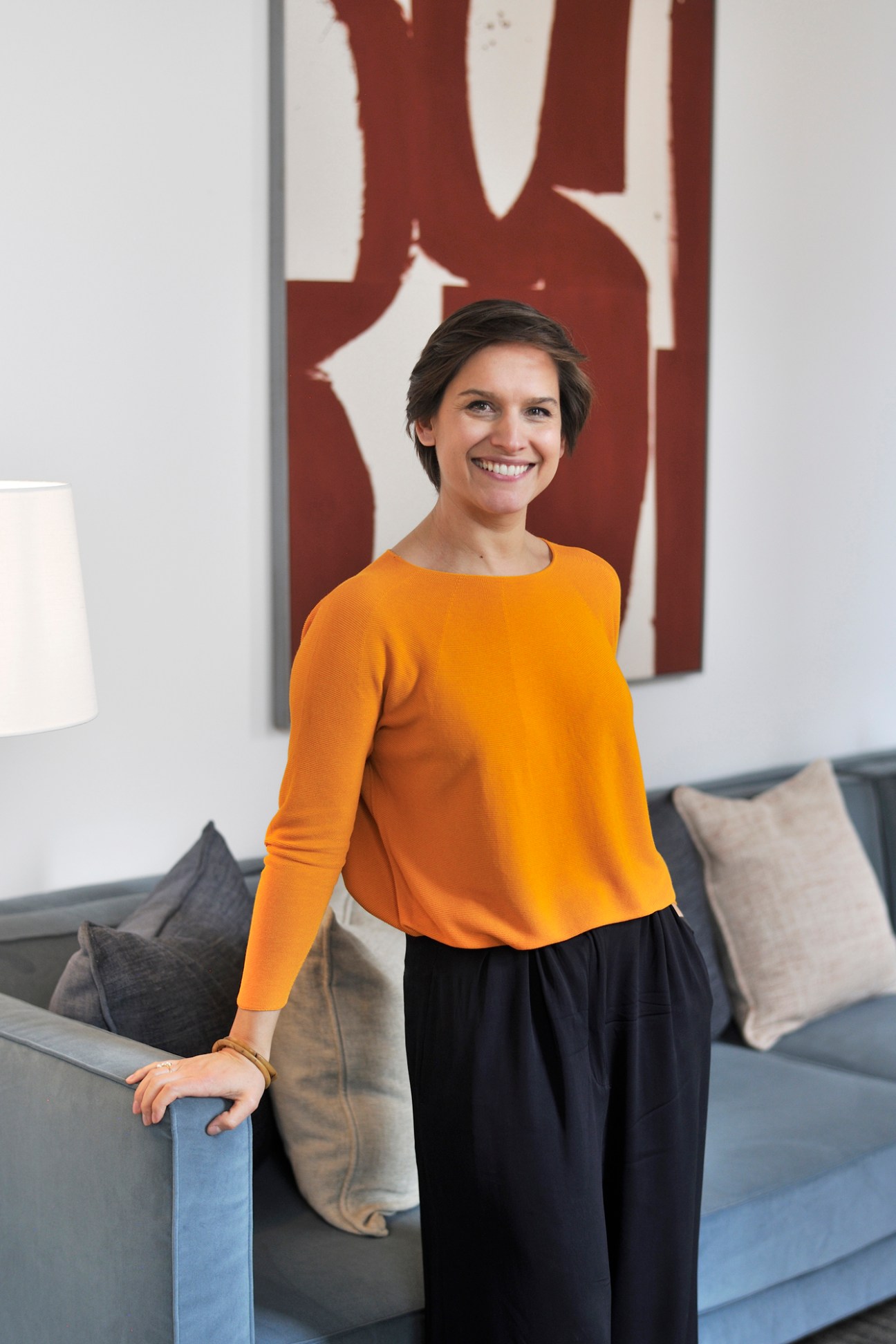 Eline Janssens, general manager of August hotel, standing in a modern interior with neutral furnishings and red artwork.
