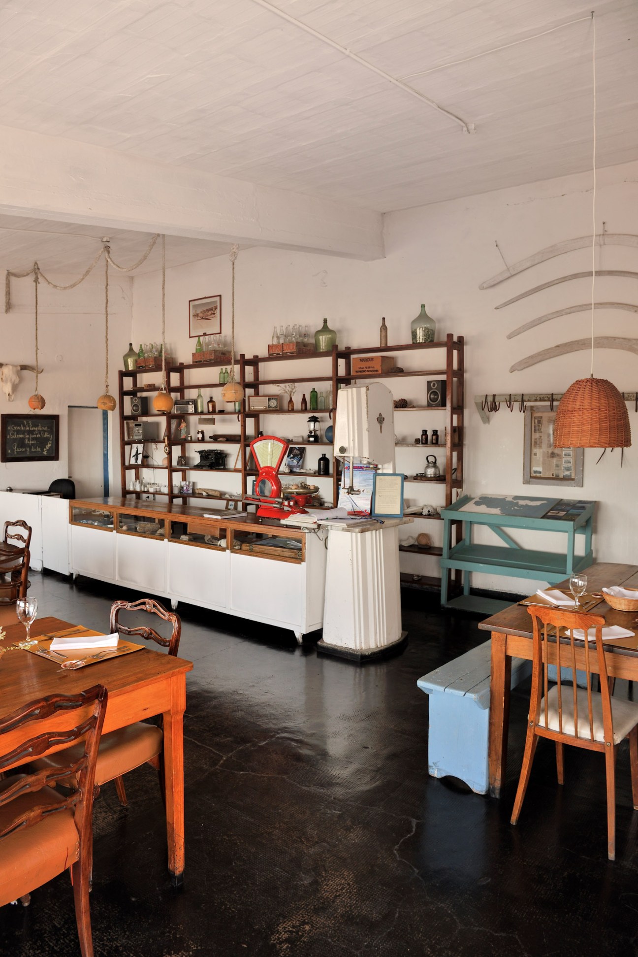 Interior of Proveeduría restaurant at Bahia Bustamante with wooden shelving, dining tables, and vintage decor.