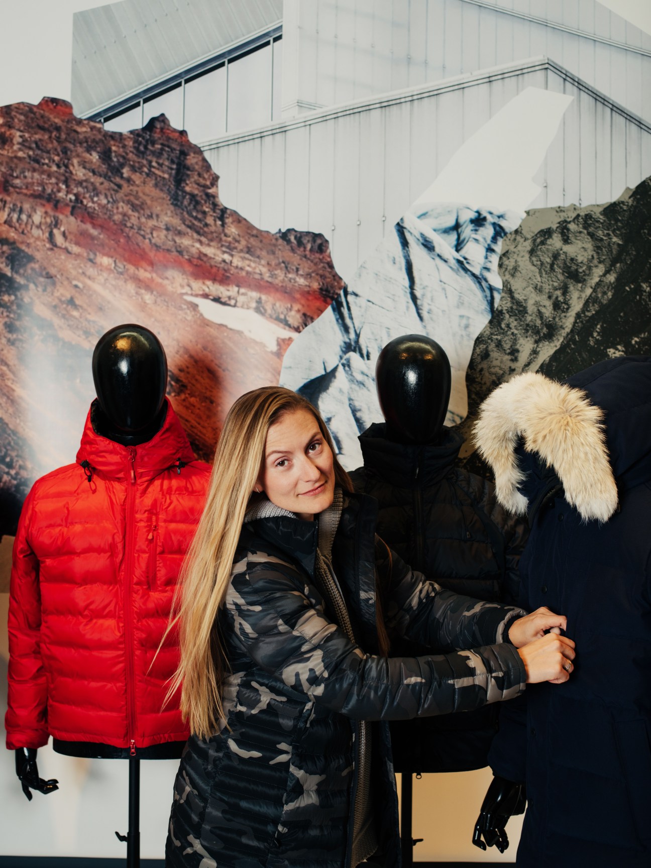 Ana Mihaljevic stands among Canada Goose parka displays featuring mannequins in red and black jackets with coyote-fur hoods