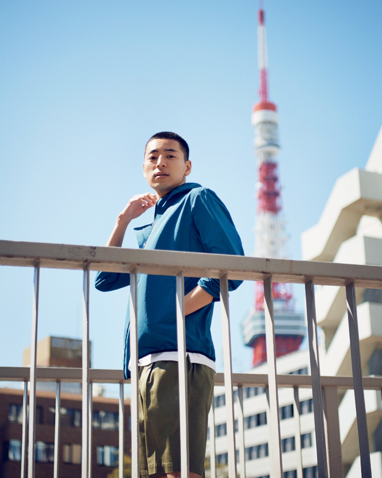 Model wearing Eleventy jacket and Hackett London shirt on Tokyo pedestrian bridge with tower in background.