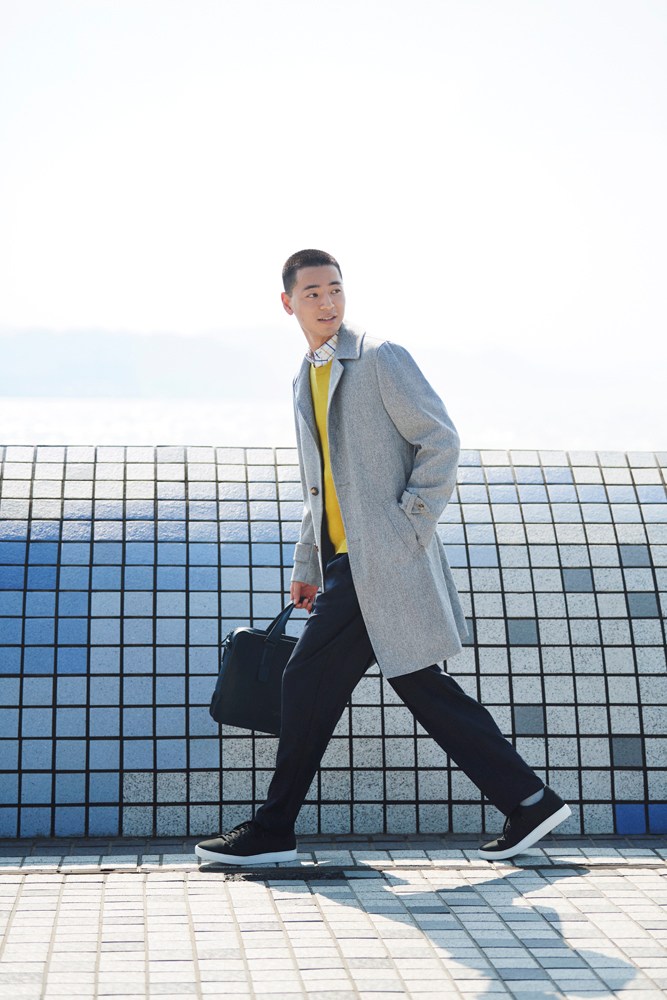 Model wearing minimalist jacket and trousers with designer backpack