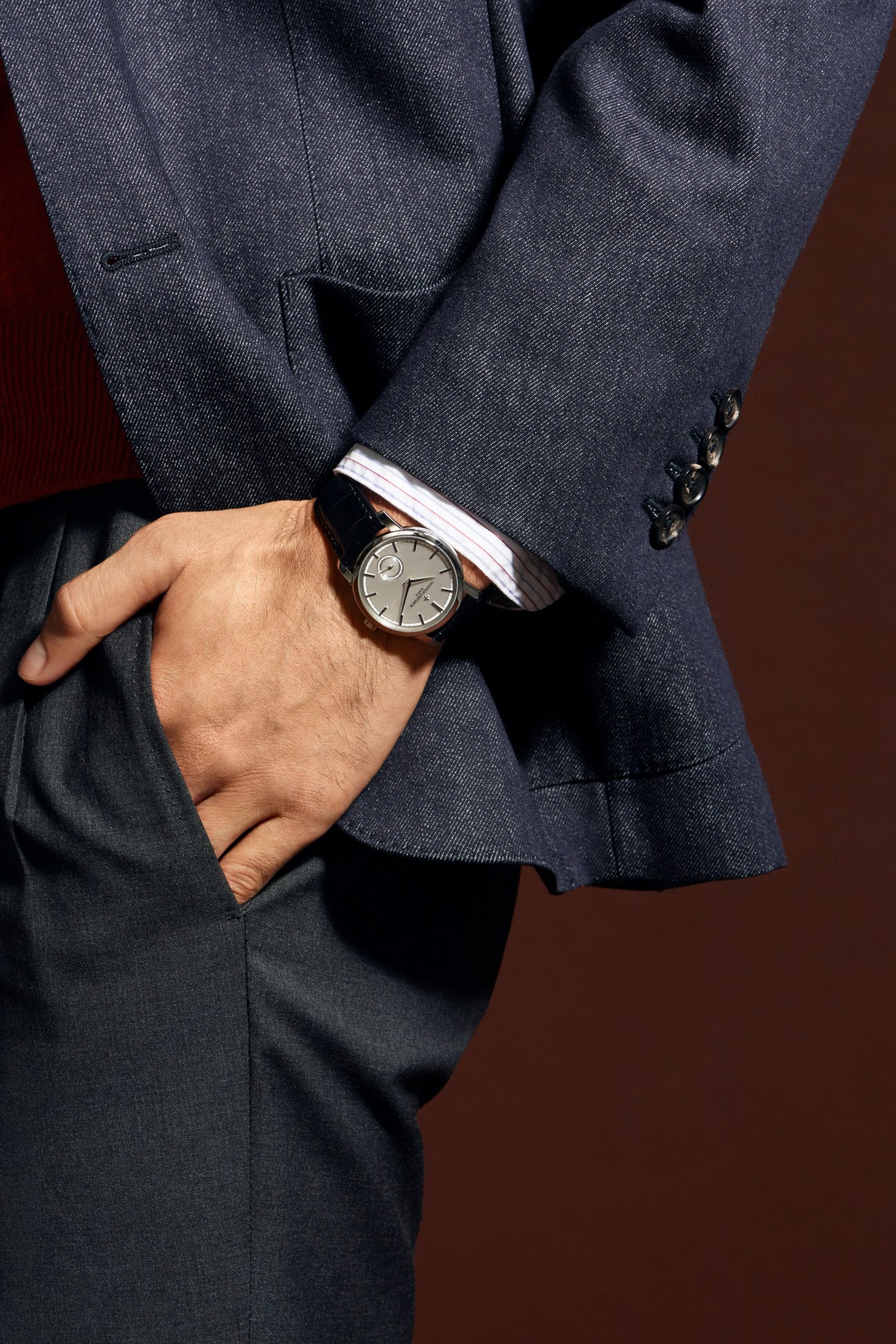 Man in navy blazer with white shirt and grey trousers wearing Vacheron Constantin watch