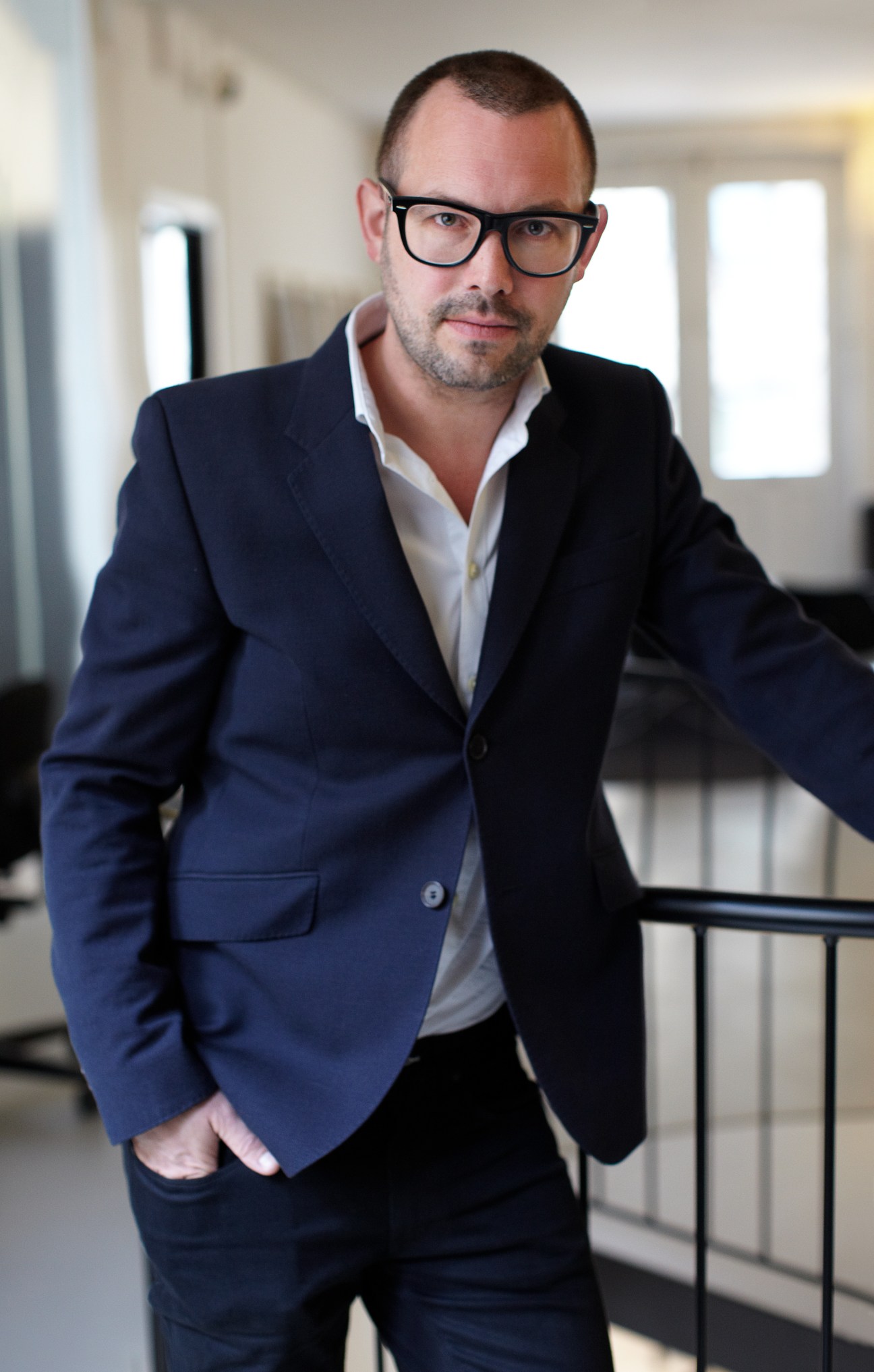 Rasmus Ibfelt, partner and strategic director of e-Types, wearing glasses and a navy blazer in an office setting.