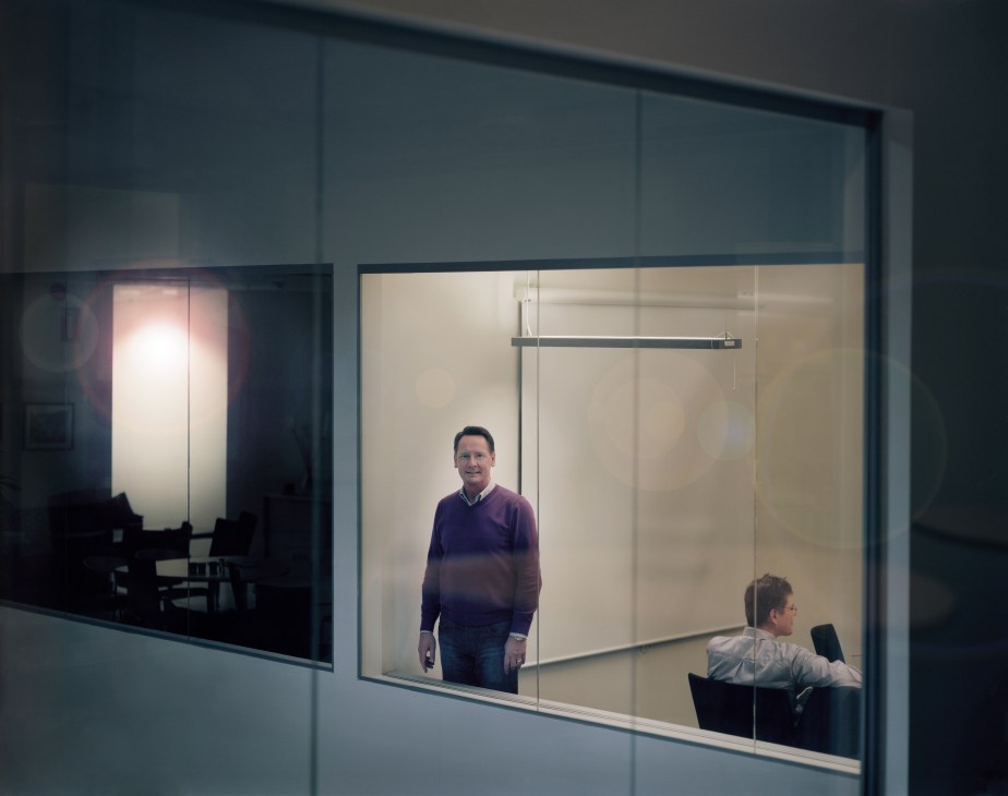 Danne Palm stands in a modern glass-walled office pod at the Inkubator in Trollhättan, with another person visible at a desk in an adjacent pod.