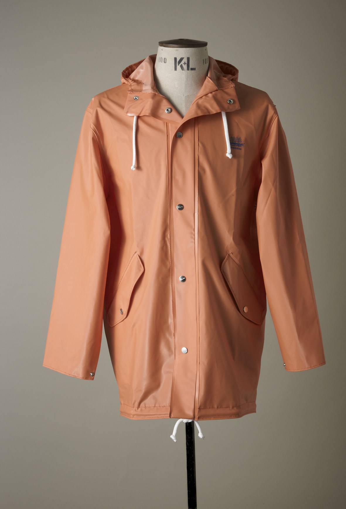Coral-pink Grundéns waterproof parka with hood and white drawstrings displayed on a dress form.