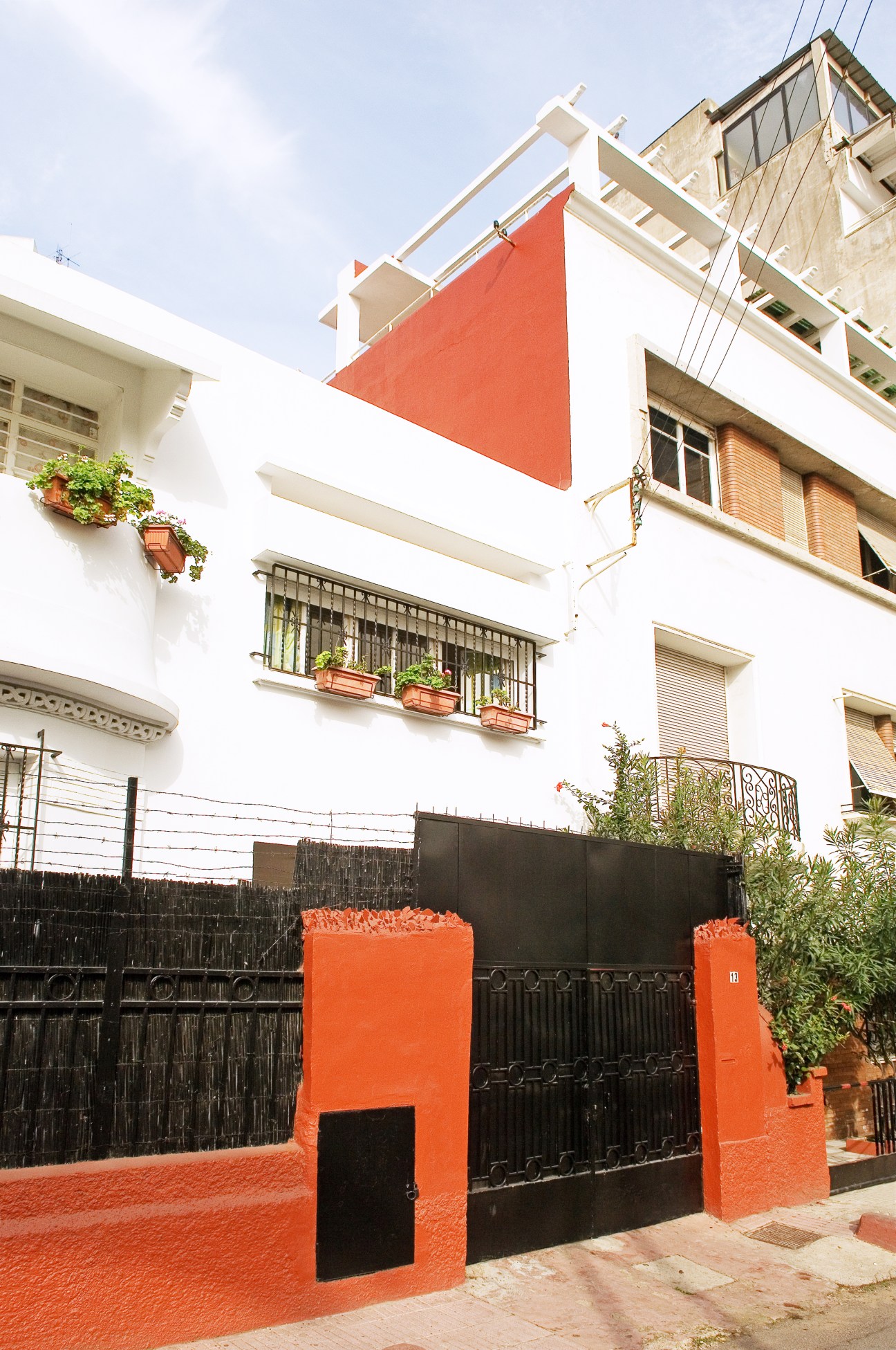Modern five-storey building in Triangle d'Or with white facade, orange accent panels, and black metal gate entrance.
