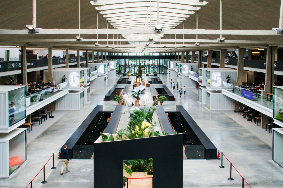 Aerial view of Station F's expansive open-plan co-working campus with multiple levels, skylights, and central planted features.