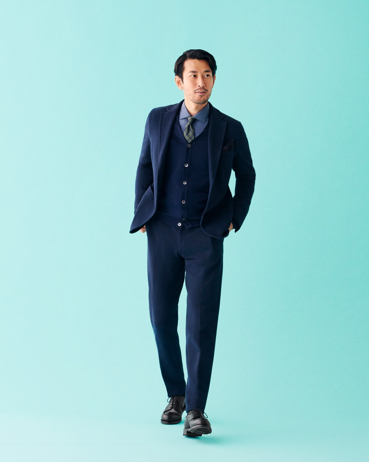 Man wearing navy Circolo 1901 jacket and trousers with Boglioli shirt and tie against turquoise background.
