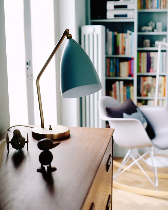 Gubi Grasshopper table lamp with teal shade and brass base on wooden desk