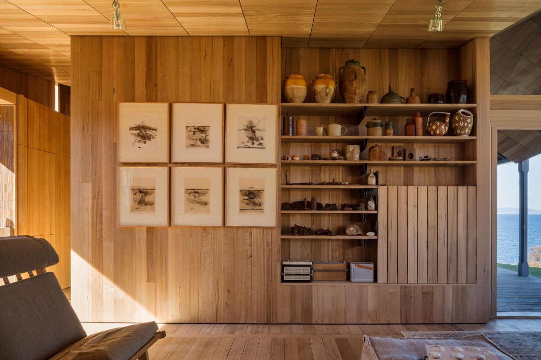 Wooden interior with framed botanical prints and shelving displaying ceramics and maritime objects.