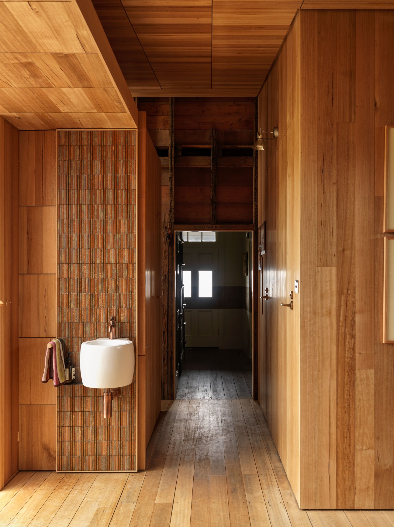 Wooden corridor with white sink basin and retractable shutters in Tasmanian oak interior.