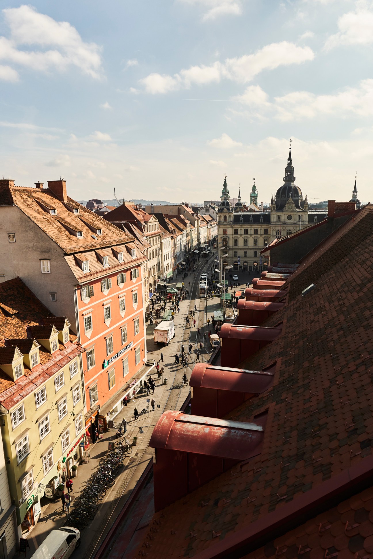 Aerial view of Graz old town showing colorful buildings, red tile roofs, and baroque church domes