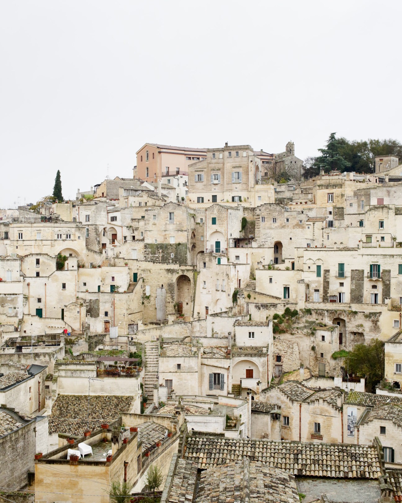 Ancient limestone cave dwellings and stone buildings stacked on a hillside in Matera's Sassi district, Italy.