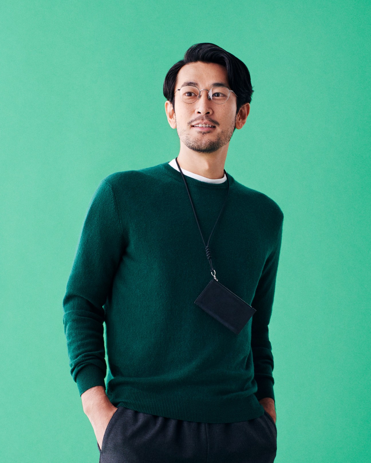Man wearing green Ermenegildo Zegna jumper and Eyevan glasses against turquoise background.
