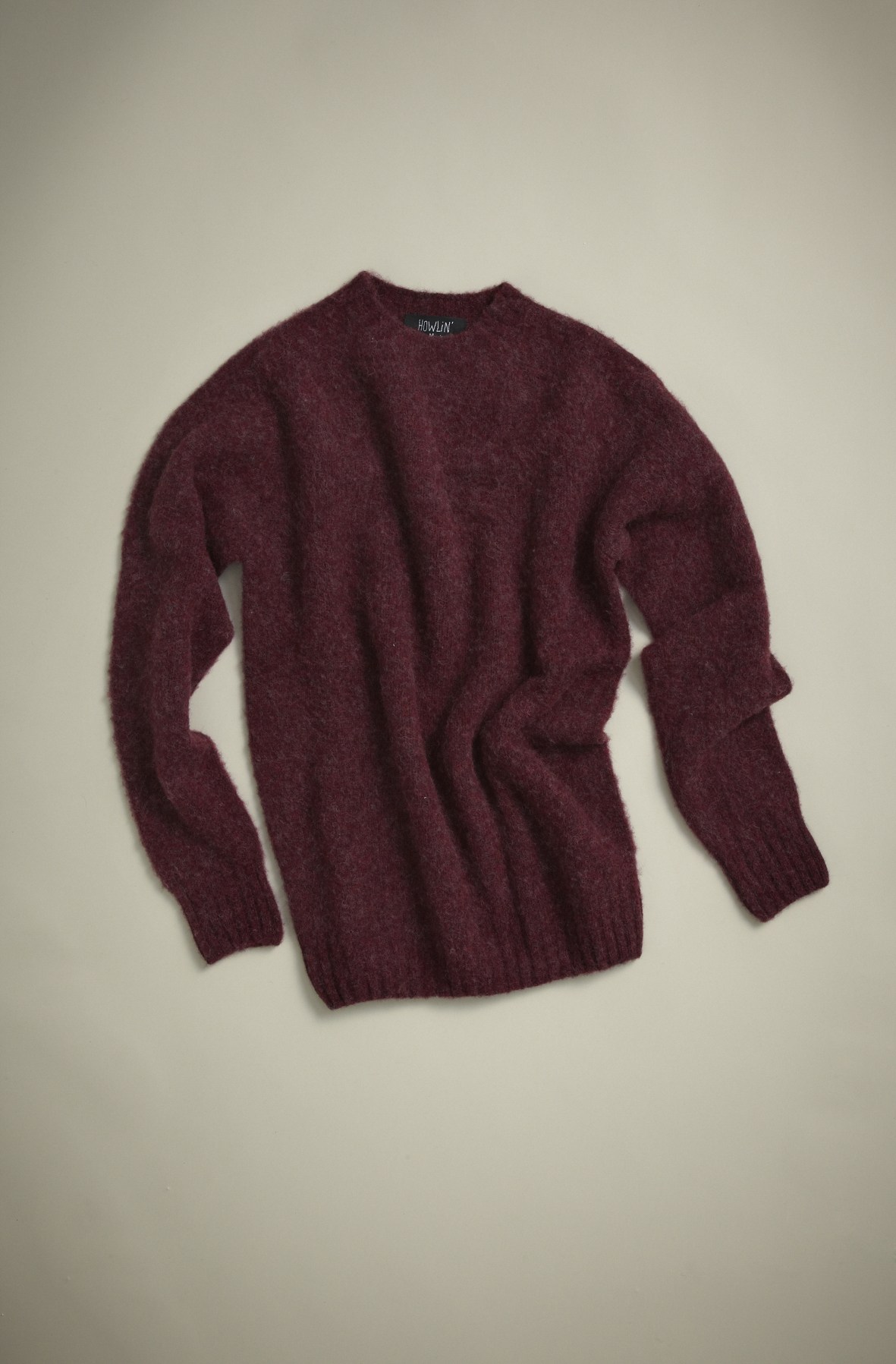 Deep burgundy knit sweater by Howlin' laid flat on neutral background.