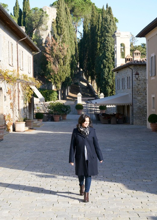 Emiko Davies walking through a stone courtyard at Rosewood Castiglion del Bosco in Tuscany.