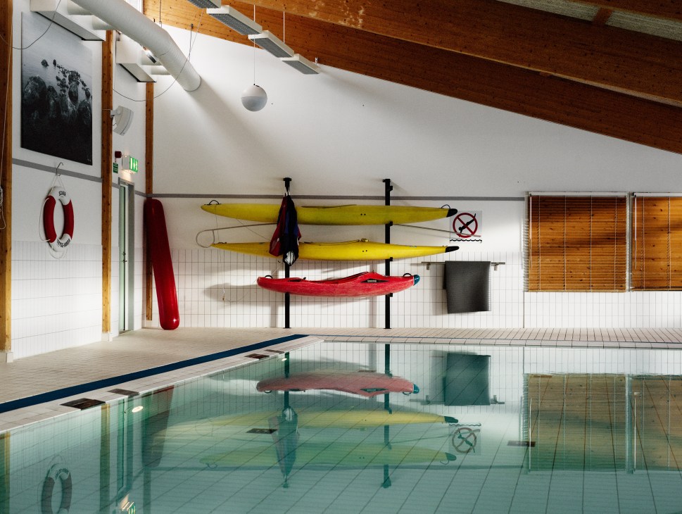 Scania's indoor swimming pool with kayaks and water sports equipment stored on the walls.