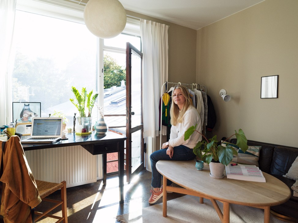 Louise Balsløv sits in her bright student room at 4th May College with desk, plants and balcony access.