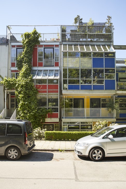 Colorful 1970s terrace houses with ivy climbing the red facade and parked cars in front