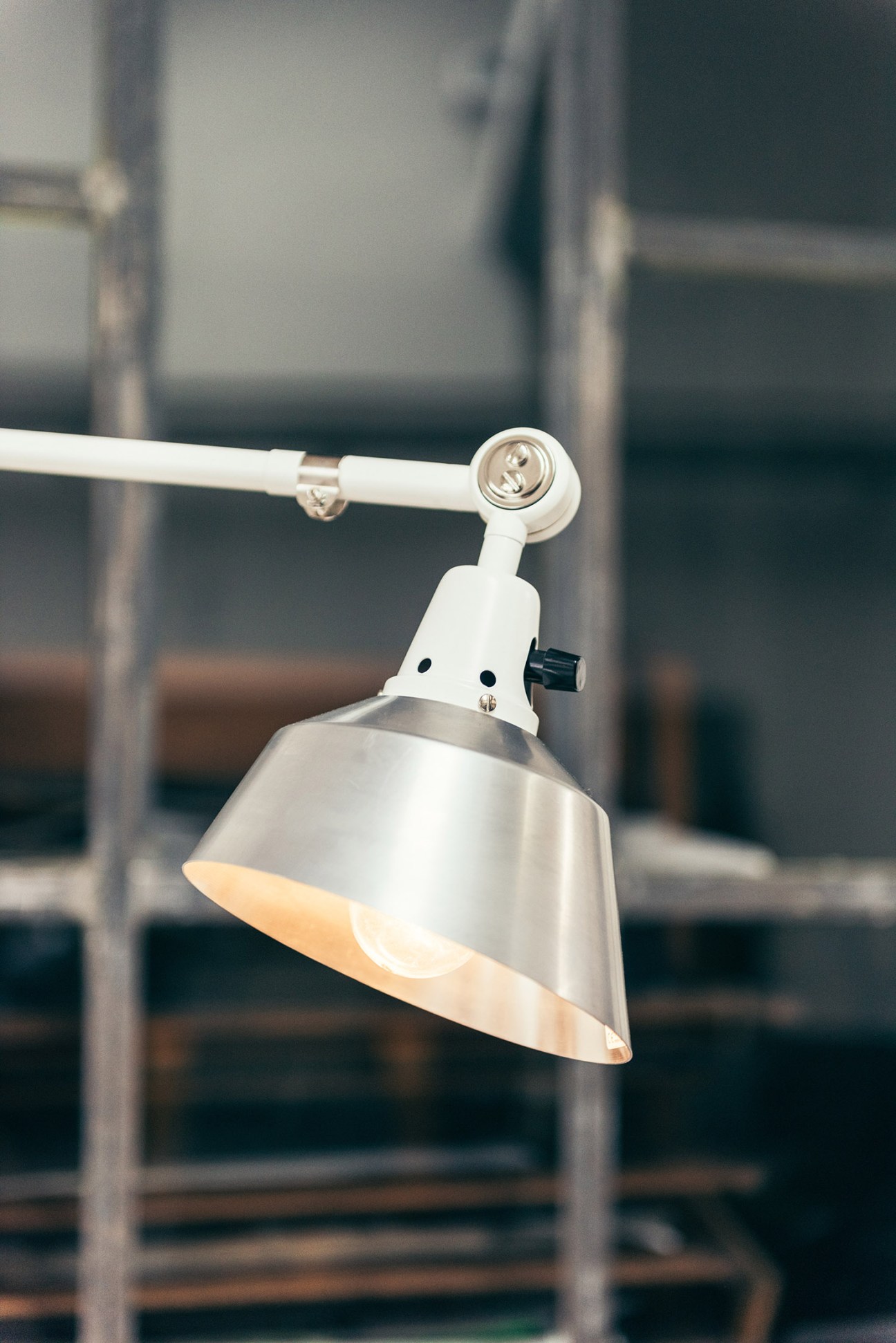 Midgard's signature modular lamp with adjustable white arm and metal shade mounted on rail.
