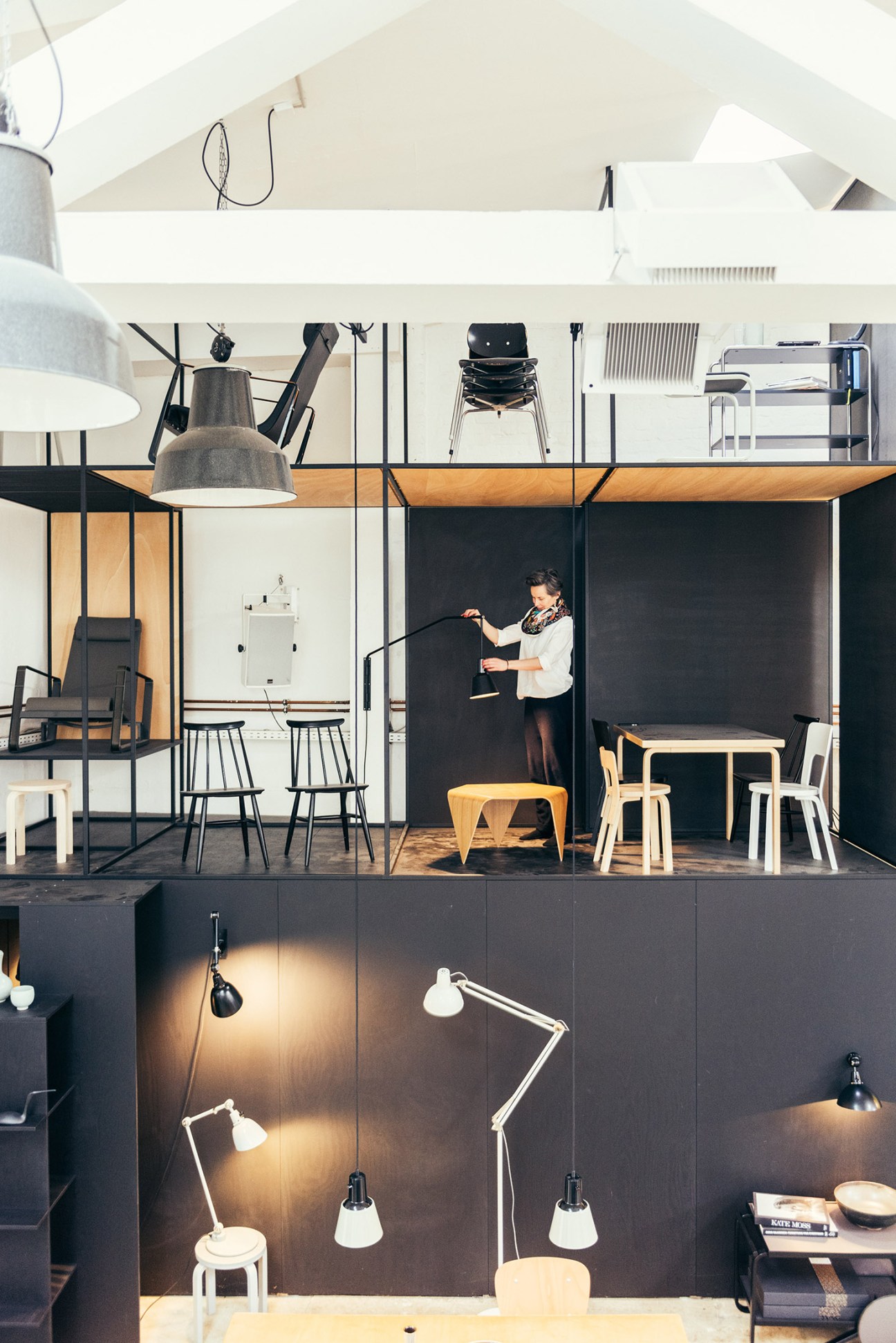 Ply Lab showroom in Hamburg featuring mid-century furniture, Midgard lamps, and a woman arranging displays.