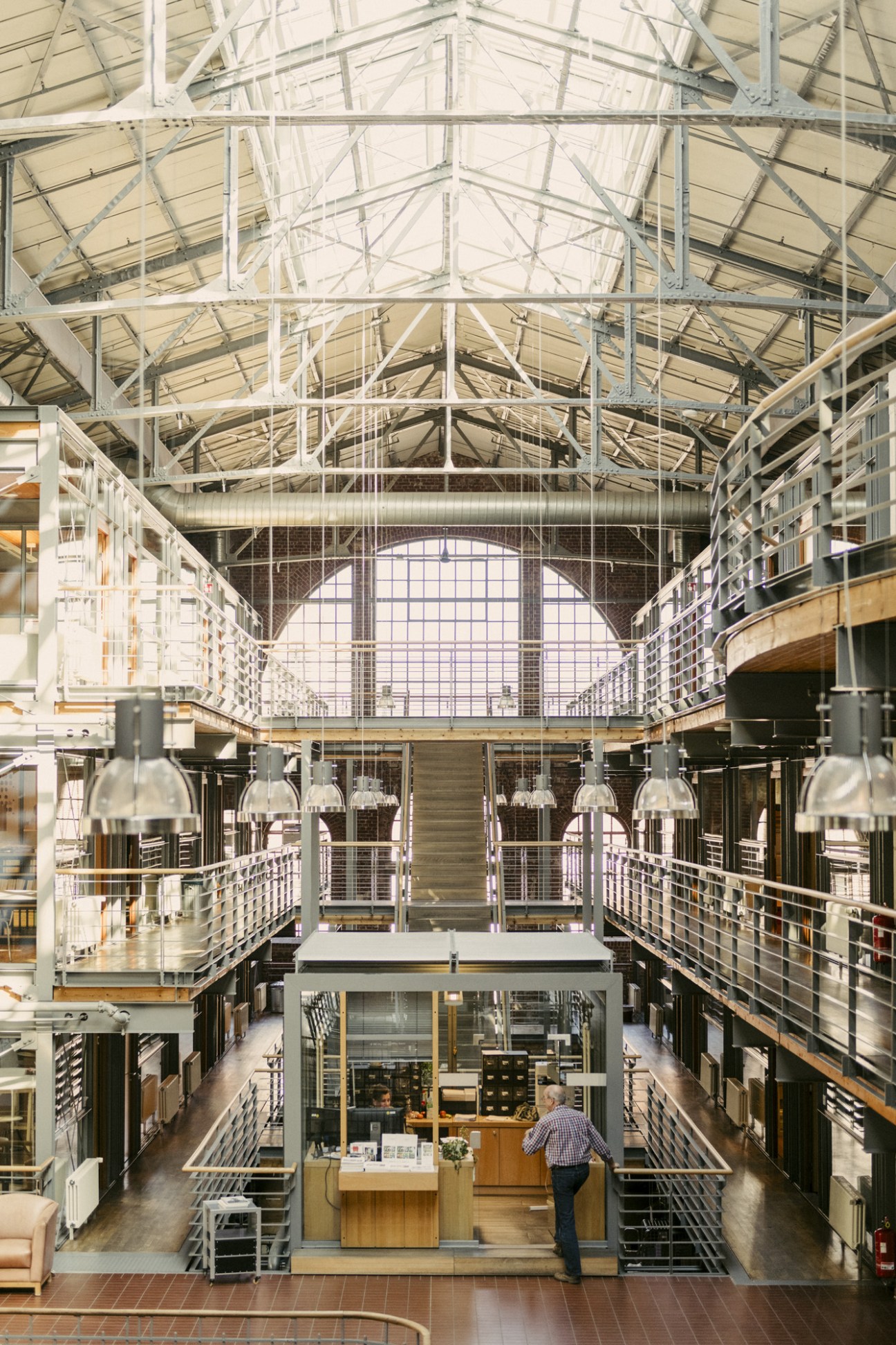 Interior of former engine hall converted into office space with stacked glass cubes and industrial steel framework under a glass ceiling.