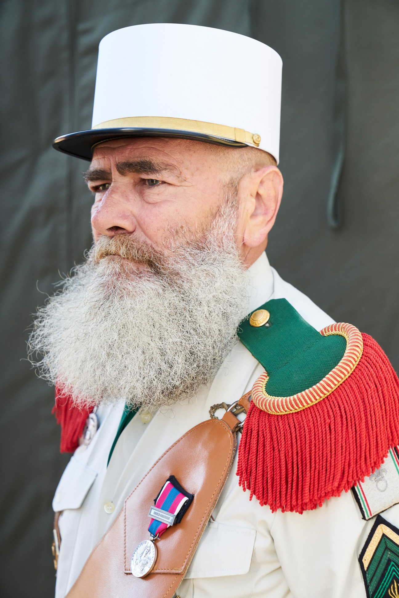 Elderly legionnaire in dress uniform wearing the distinctive white képi blanc cap and red épaulettes