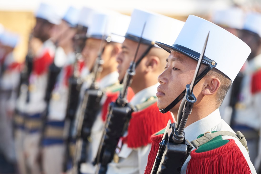 French Foreign Legion soldiers in formal dress uniform with white képi blanc caps and red épaulettes standing in ceremonial formation.